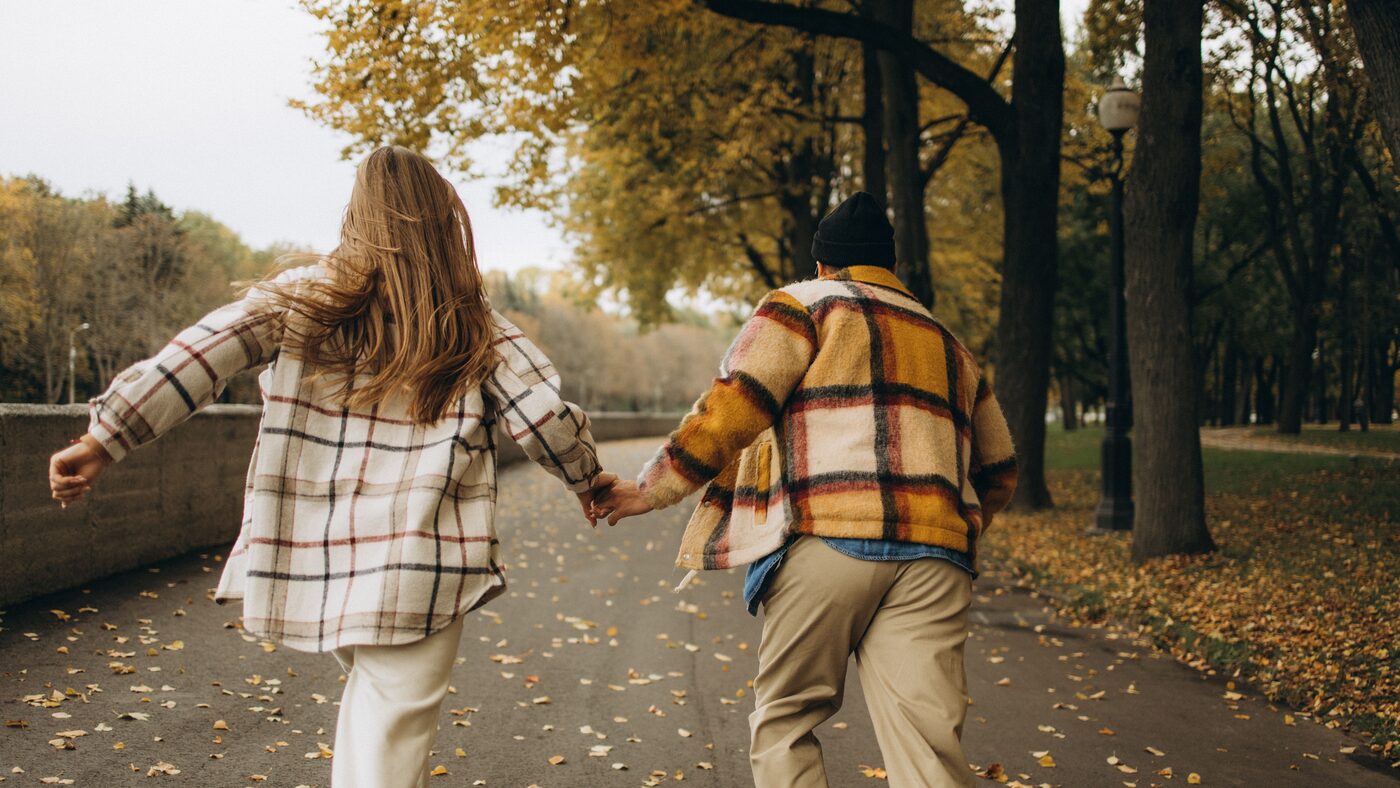Couple running hand in hand through an autumn park